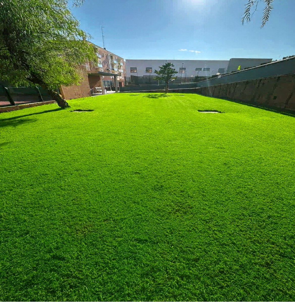Zona verde comunitaria con césped uniforme y corte técnico