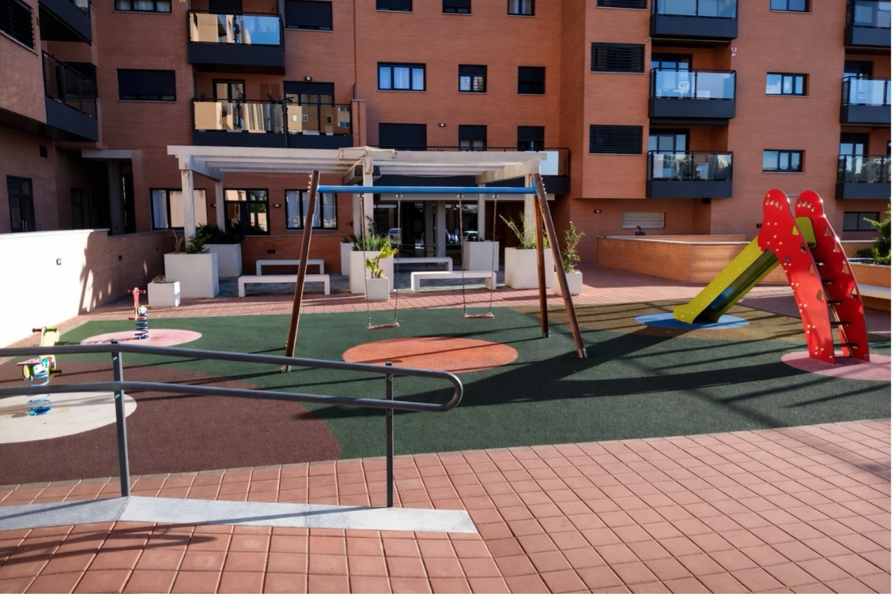 Área comunitaria infantil con mantenimiento exterior y césped en buen estado
